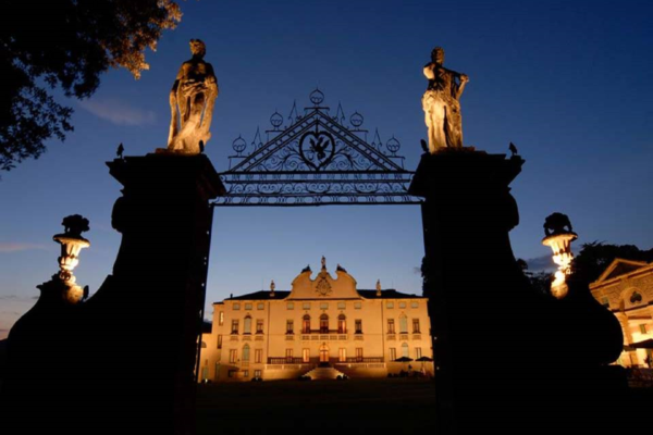 Vista notturna del cancello della Villa di Montruglio e sullo sfondo la facciata con l'illuminazione